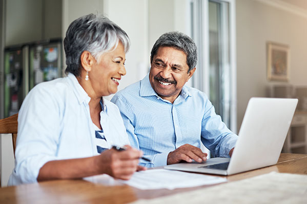 An older couple sitting at a table using a laptop