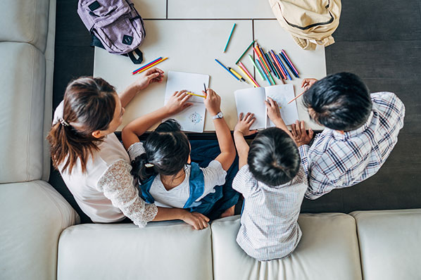 A family of four drawing at a table
