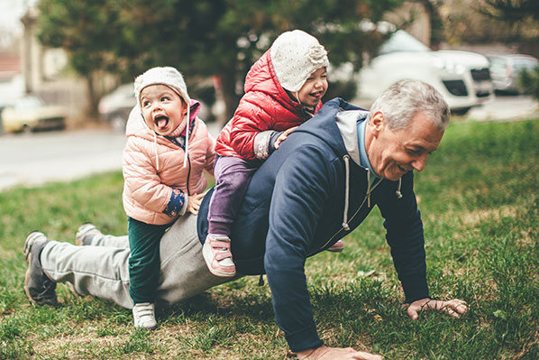 An elderly man playing with two grandchildren