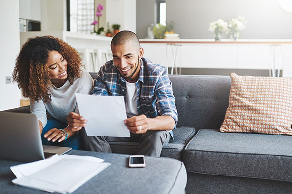 A younger couple reviewing a document while seated on a couch