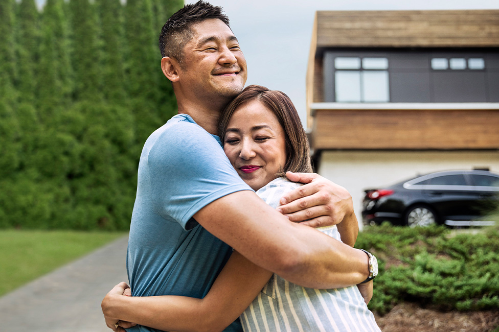 man hugging a woman in front of a house