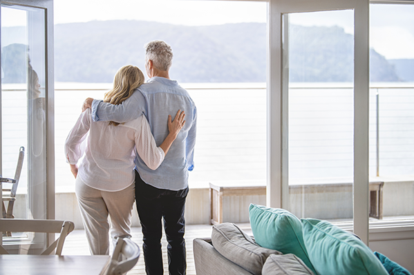 A man and woman with arms around each other while staring out into the lake view