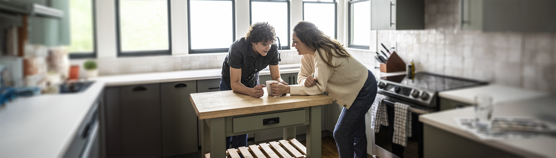 Two people leaning over a kitchen island having a discussion