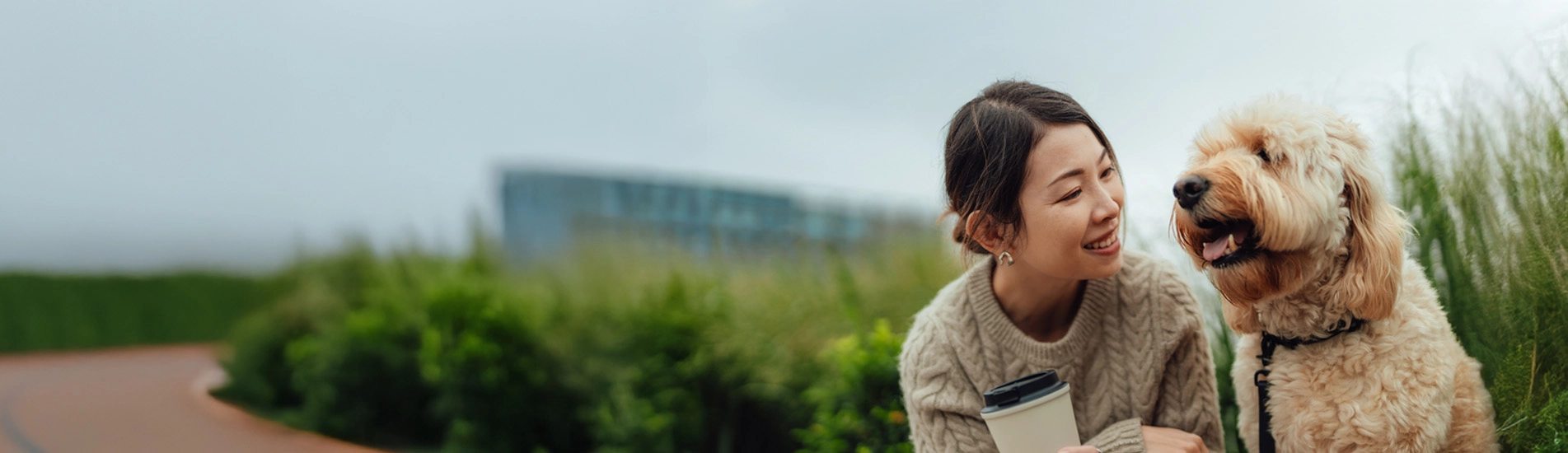 an Asian woman in her 30s leaning in to speak to her fluffy white dog